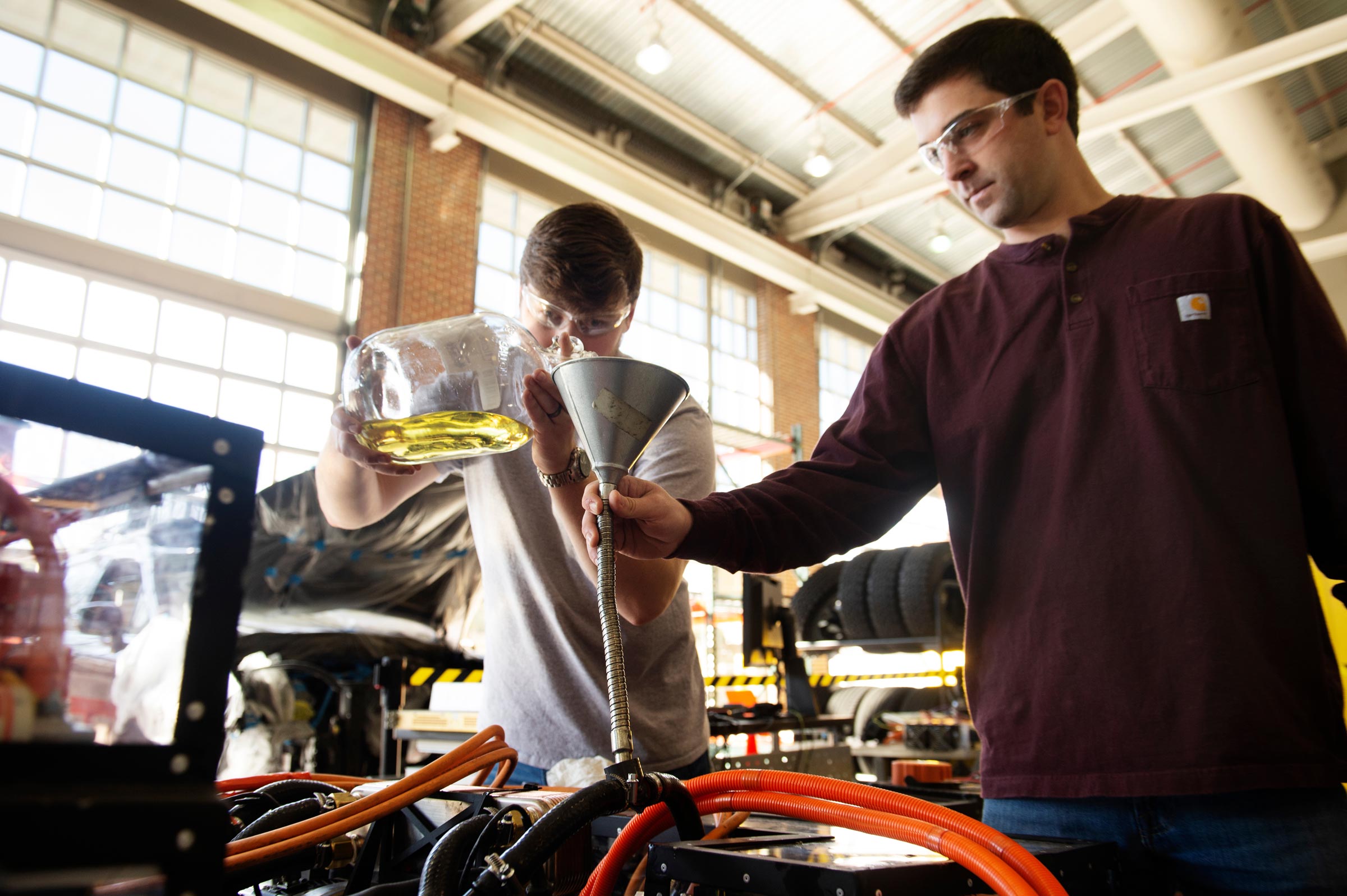 Chad Leachman, left, a graduate student in mechanical engineering from Ruston, Louisiana, tops off the Halo Car's power line drive opticool fluid. Assisting is Andrew LeClair, research engineer II at MSU's Center for Advanced Vehicular Systems.