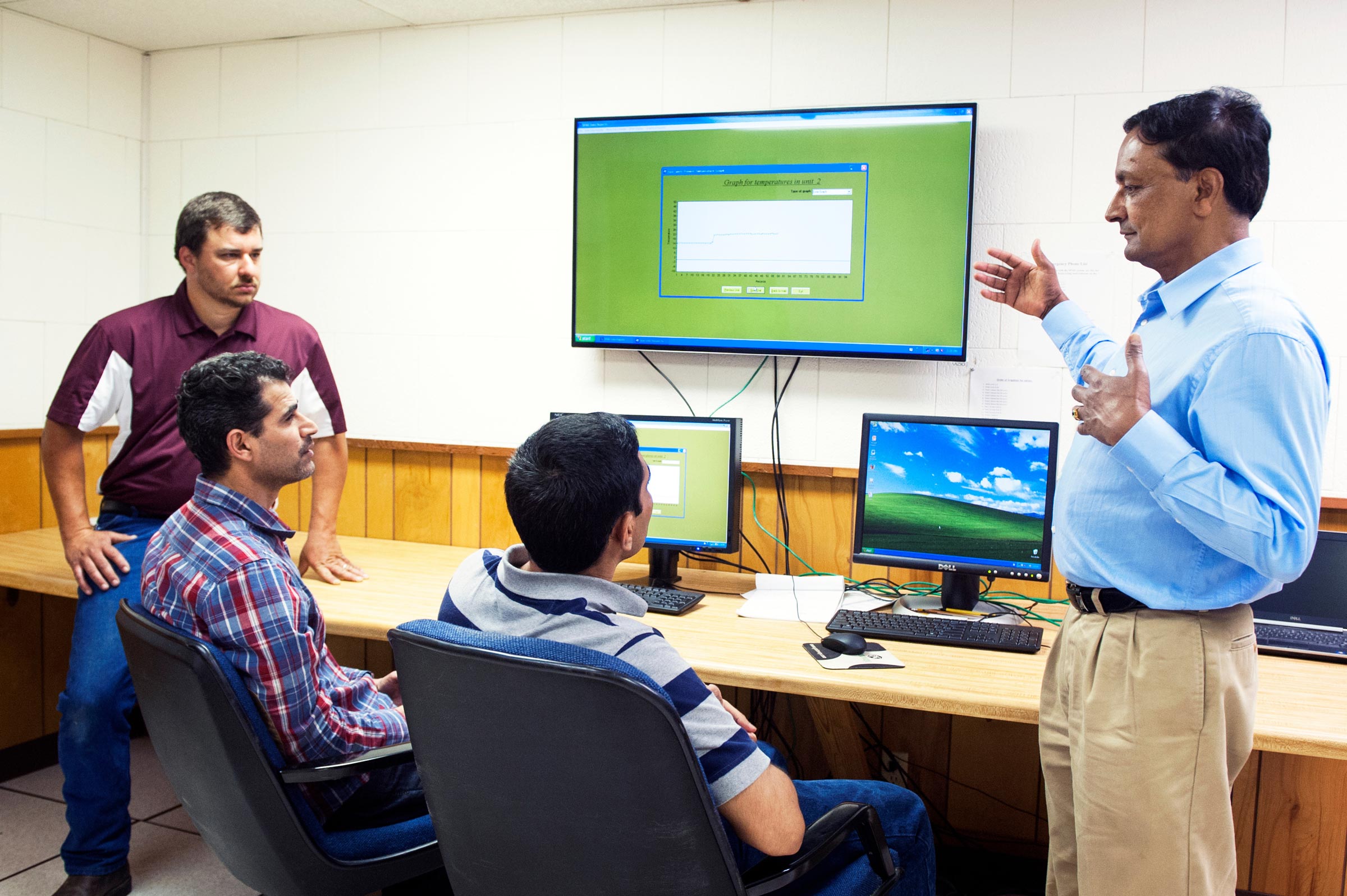 Teacher speaking with students at computers