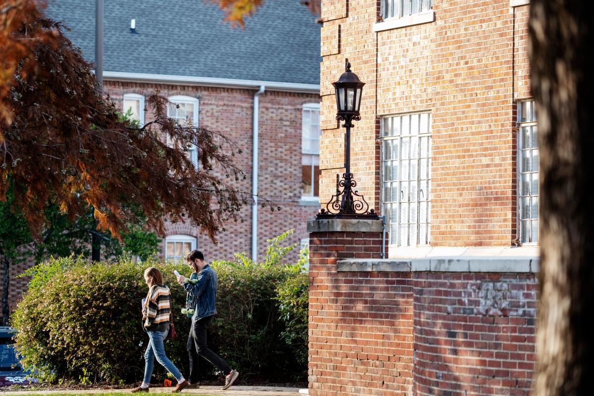 Two students walking by Magruder Hall in the fall